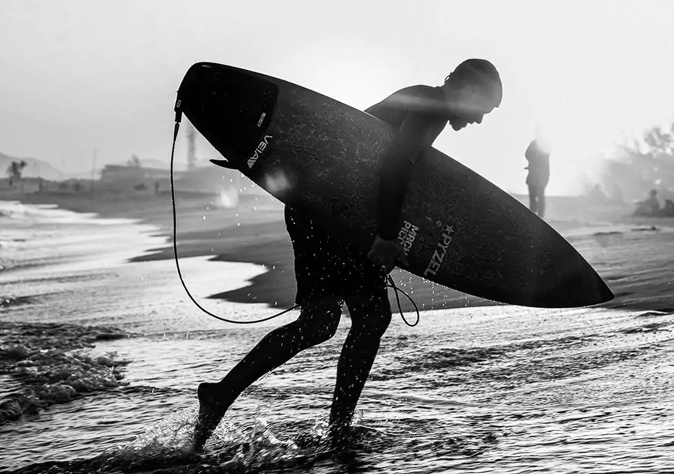 Surfer carrying a board down Playa Grande at first light, Dominican Republic